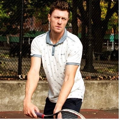 Alex Cherman, head coach, holding a tennis racket