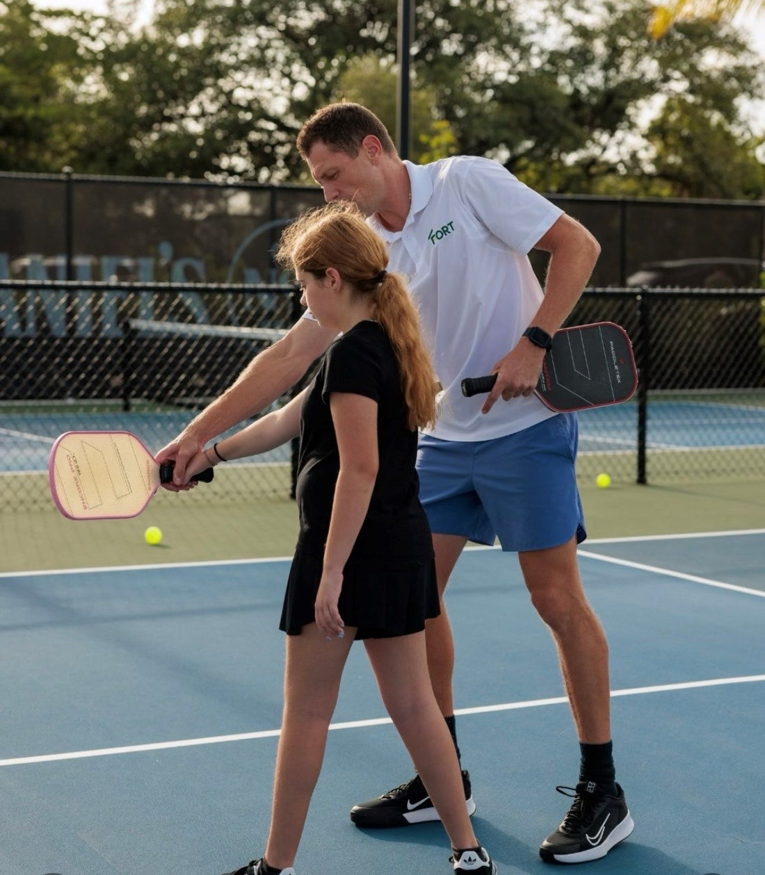 Alex coaching a junior player's paddle grip on a pickleball court